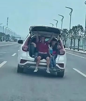 猖狂！宜宾一辆行驶途中的小车，3人挤在后备箱拿手机自拍！-2.png